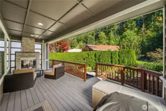 The outdoor space is dreamy with this stone stacked fireplace and Shoji privacy screens, Trex decking overlooking the mature hedges and greenspace.