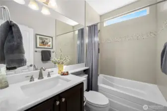 Guest bath with Quartz counters, upgraded tub with tile surround and tiled flooring.