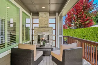 The outdoor space is dreamy with this stone stacked fireplace and Shoji privacy screens, composite decking overlooking the mature hedges and greenspace.