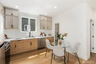 A deep sink with a sleek swan-neck faucet sits beneath a large kitchen window that floods the space with natural light, framed by a timeless subway tile backsplash.