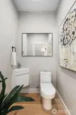 Sleek and modern half bath on the main living level, featuring a space-saving vanity  and stylish finishes.