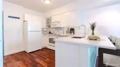 Sleek all-white kitchen with functional island bar perfect for cooking and casual dining.