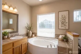 Primary ensuite featuring a soaking tub with a relaxing view - virtually staged.