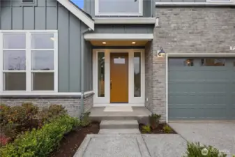 Covered Entry:  A warm wood-tone door anchors the sheltered entryway, framed by sidelights that draw natural light into the foyer while highlighting the clean exterior palette. The generous overhang and simple landscaping provide a comfortable transition between the outdoors and the home’s interior. Located in Bothell’s Canyon Park corridor, the entry sets the tone for a lifestyle centered around convenience, access to trails and dining, and an easy commute to I-405. The understated detailing adds a refined, modern character that welcomes guests with simplicity and style.    These photos are from Lot 5 at Gooden Hollow, the home listed here. However, other homes in the community will have changes, so all photos, renderings, site maps, and floorplans are for visualization purposes only. Plans, colors, building orientation, finishes, home outlook, and other details can and WILL vary.