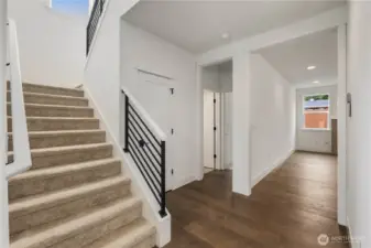 Stairway & Lower Hall:  The wide lower hallway connects key main-level spaces, while the open stairway brings natural light from the upper landing into the heart of the home. Its layout allows for smooth circulation between the great room, kitchen, den, and main-level bedroom. Located in the Canyon Park area of Bothell, the home’s thoughtful design pairs modern architecture with proximity to Northshore schools, commuting corridors, and neighborhood amenities. Clean lines, metal railing accents, and warm flooring lend the hallway a contemporary, welcoming feel.    These photos are from Lot 5 at Gooden Hollow, the home listed here. However, other homes in the community will have changes, so all photos, renderings, site maps, and floorplans are for visualization purposes only. Plans, colors, building orientation, finishes, home outlook, and other details can and WILL vary.