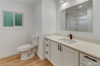 View of newly updated primary bathroom with new flooring quartz counters brushed nickle lighting new cabinets undermount sink and large mirror to get ready by