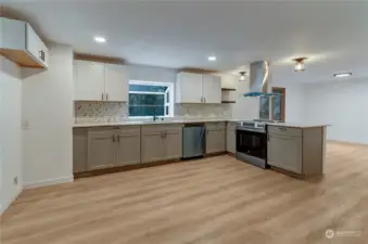 View of new modern design kitchen with new cabinets oil rubbed fixtures ss appliances white slab stone quartz counters and hood.  There is room for all your kitchen activities here.  Dont miss the large garden window above sink to view more nature settings outside