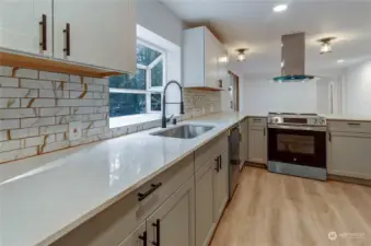 Closer look at new modern kitchen with artistic glass tile backslash goose neck faucet and vinyl hard wood flooring for low maintenance