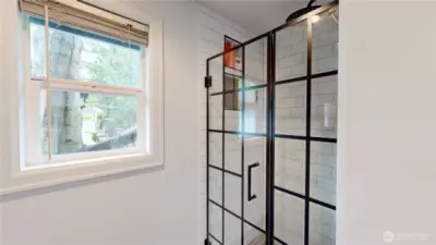 Primary shower features large subway tile and decorative glass door enclosure.