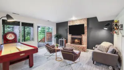 Lower level recreation room features a brick surround wood burning fireplace and hearth