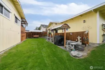 Backyard set up with covered BBQ area and swing.