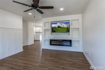 From the main entry stepping into the living room.  Nice wainscotting accent wall on the left.  Flat screen TV stays with home, electric remote controlled fireplace & cool art niches.