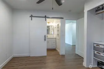 Second view of the primary suite with barn door to the private bathroom.