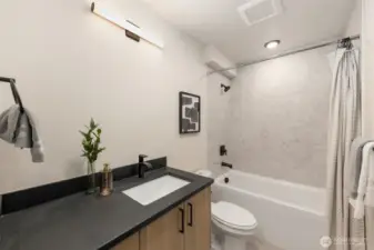 Matte black finishes, designer fixtures, and a floating vanity create a crisp, contemporary feel.