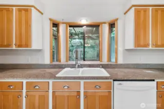 Bay window in kitchen provides views to natural landscape.