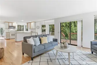 The family looking towards the kitchen and casual dining area. Slider provides direct access to the backyard and a expansive deck that connects to the dining room, expanding your options for seamless indoor-outdoor entertaining.