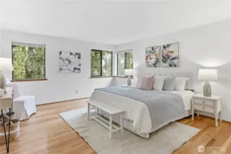 Spacious, light-filled primary suite easily accommodates a king-sized bed and nightstands, with hardwood floors extending through all the bedrooms for a cohesive, polished look.