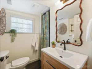 The refreshed lower-level 3/4 bath shines with new flooring, a stylish vanity, updated mirror, modern lighting and convenient added shelving.