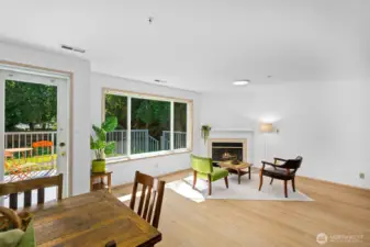 Large open living and dining area filled with light, picture windows, gas fire place and open to balcony and shared fenced in yard
