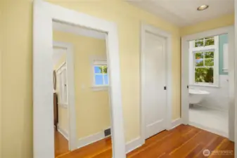 In the primary suite hallway, a walk-in closet sits opposite the entry to the light-filled upstairs bath.