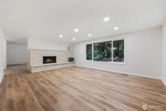 Living room with wood fireplace and oversized window looking over back yard.