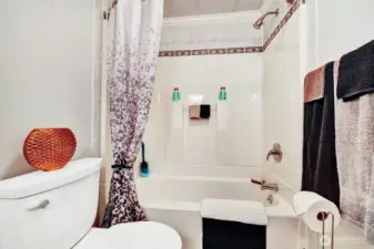 Squeaky clean tub surround with custom tile work at the top in the full guest bathroom that is steps from the guest bedroom and has access door to the utility room.
