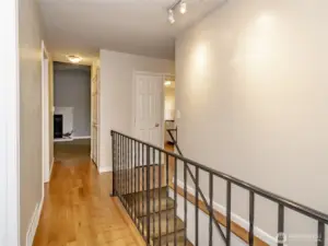 Main Floor hallway to downstairs, Bedroom, Primary Bedroom, and Main floor Bathroom on right; and Kitchen, Dining room, and Livingroom on Left.