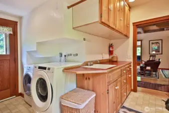 We are back at the front of the home to the walk through laundry and mud room adjacent to the Living Room and also accessible from the covered porch (door along left edge of photo). There is a half bath to your back (next photo).