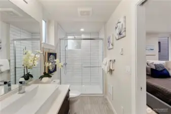 Primary ensuite bathroom with featured trough sink, walk in tiled shower, and built in shelving.  Picture of the clay color scheme of a previous model home.