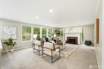 Bright Living Area with Fireplace and Wall of Windows Overlooking Private Setting