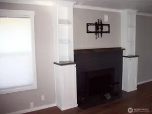 Wood burning fireplace is framed by matching pillars, which add balance and a special area for books, art pieces or just knick-knacks.  The bonus wall mounted TV bracket and soundbar will stay for your added enjoyment (or we will remove it and refinish the wall)