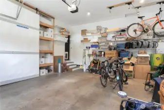 Impressively large two-car garage with a soaring ceiling and custom built-in shelving behind sliding barndoors.