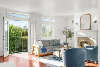 Generous living room with great western natural light, gas fireplace, wood floors, and Juliette balcony