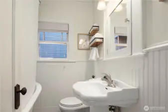 The main bath offers timeless charm with wainscoting, pedestal sink, and a clawfoot tub with shower.