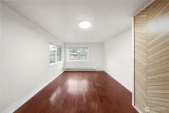 This bright and airy room features spacious dimensions, abundant natural light through large windows, and beautiful hardwood flooring.