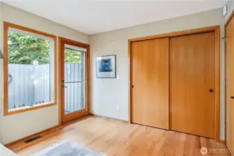 The guest bedroom/flex room with lot of closet space, beautiful hardwood floors, and outdoor access to the lovely fenced-in patio, that also has an entrance beyond to the front driveway.