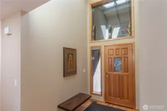 The entryway is spacious with vaulted ceilings, natural light and a beautiful free-floating wood bench and real hardwood floors.