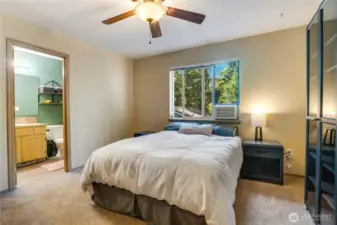 The primary bedroom can easily accommodate a king size bed with plenty of room for additional furniture without sacrificing the ability to reach the ensuite bath. Note the ceiling fan to keep cool air moving from your window AC unit (that stays with the home!)