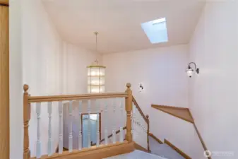 The staircase features a custom chandelier and a skylight, as well as wall sconce lighting