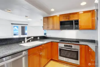 Open kitchen with granite countertops & SS appliances.
