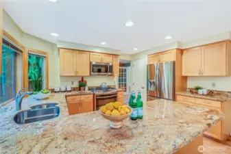 The centerpiece of the kitchen, this spacious granite-topped breakfast bar offers ample counter space for meal prep and casual dining. Refinished hardwood floors add warmth and elegance to the space.