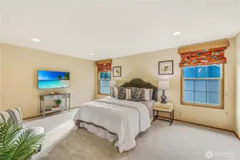 This spacious primary bedroom is a private retreat with new plush carpeting, recessed lighting, and large windows that invite in natural light. The neutral tones create a soothing environment, perfect for rest and relaxation.