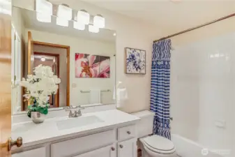 This updated bathroom features a sleek vanity, framed mirror, and modern lighting. A combination of neutral colors and quality materials makes this space feel fresh and contemporary.