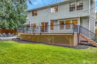 From this angle, the home’s tiered outdoor living spaces become apparent, offering multiple areas for relaxation and recreation. The gentle slope of the yard creates visual interest while maximizing usable space.