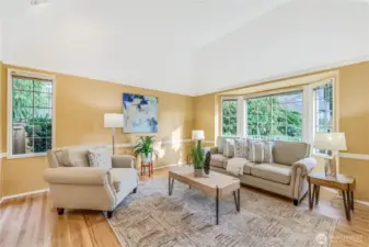 A vaulted ceiling and oversized bay window flood this room with natural light. Crisp white trim and refinished hardwood floors provide a neutral canvas, ready for your personal touch.