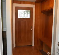 Beautiful entry door with convenient coat and shoe area and a place to sit.