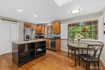 Spacious kitchen with granite island, stainless steel appliances, and breakfast nook overlooking the peaceful front yard.