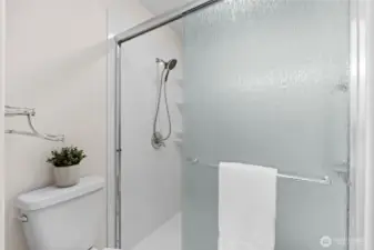 Primary shower with sleek walk-in sliding glass doors.
