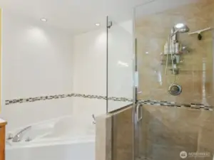 Modern soaking tub and shining shower with beautifully designed tile/granite crftsman detail.