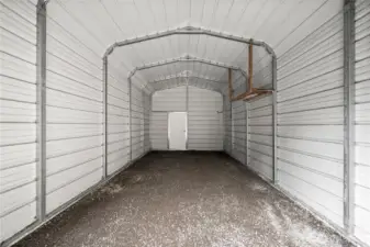 Fully enclosed metal carport with roll up metal garage door.